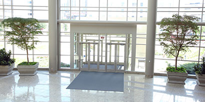 View of sliding doors and lobby of clean commercial building with many windows.
