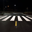 Low-angle shot of white painted crosswalk across road.