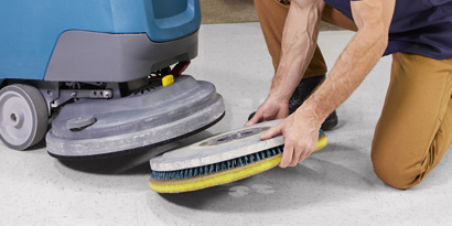 Worker replacing 3M Floor Pad on floor buffer.

