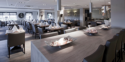 A restaurant full of set tables has attractive finishes on its countertops and floors.

