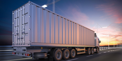 Large container heavy vehicle driving off on the highway against the evening sky.