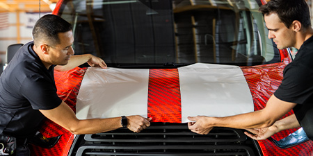 两名安装工在引擎盖上定位 IJ280 膜
