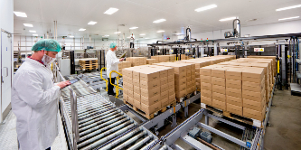 Image of masked workers in a clean white room keeping track of stacks of packages
