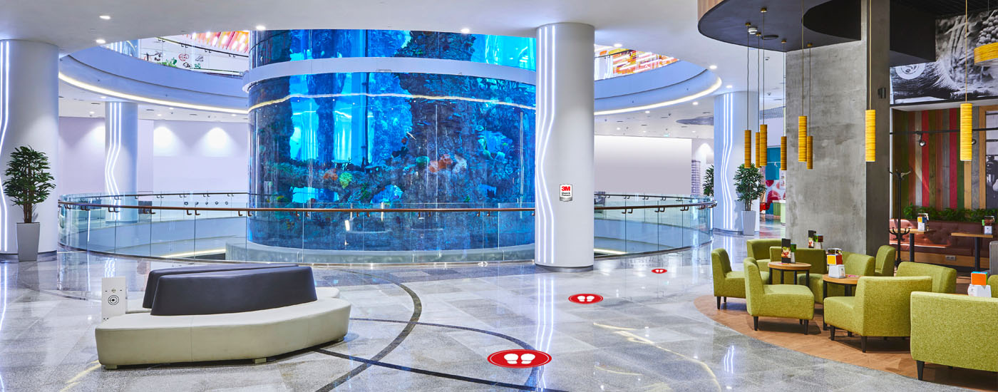 bright and clean retail lobby with seating areas for dining and relaxing, next to an aquarium display in center of the facility
