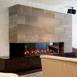 A modern fireplace has architectural finishes that have the appearance of stone.
