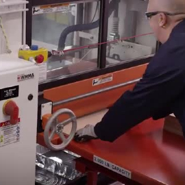 Video still of a working sliding a piece into the machine for coating