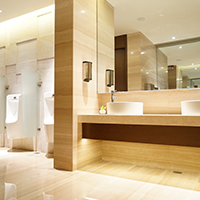 A modern public restroom has a shiny floor and wood-patterned wall covering.