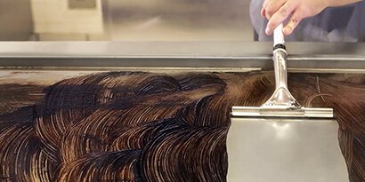 A restaurant worker cleans a griddle with the Scotch-Brite™ Griddle Cleaning System.
