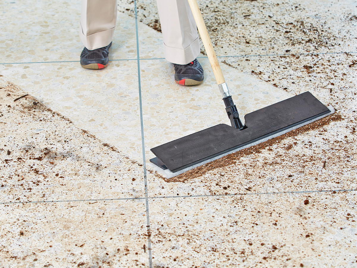 A worker using a buffer to treat a shiny floor.

