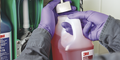 male service contractor filling a chemical management dispenser with 3M chemicals
