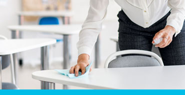 school teacher disinfecting desks in the classroom.