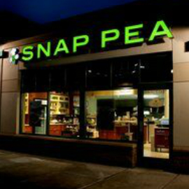 Exterior of restaurant with illuminated sign lettering reading, “Snap Pea.”