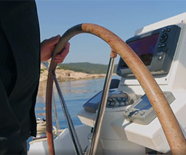 Video still showing a nautical steering wheel and instrument panels