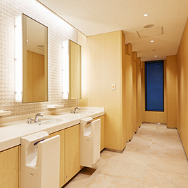 Public restroom with light wood finishes on walls and cabinets.