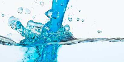 blue chemical being poured into a water solution.
