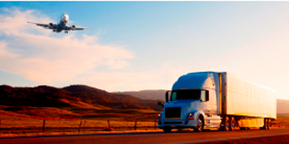 一辆商用卡车行驶在高速公路上，头顶上飞过一架飞机
