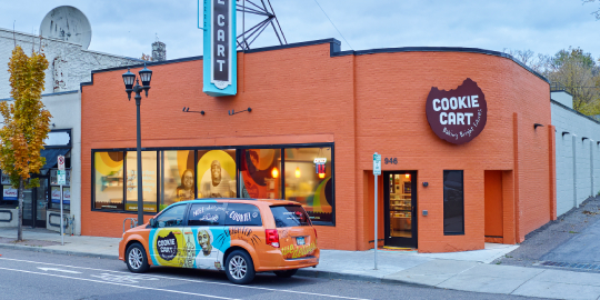 Illustration of café with seafoam green wall wrap, sign and booths.
