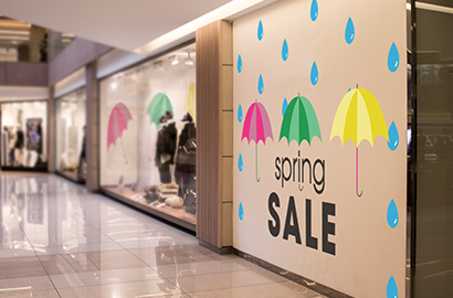 Wall wrap on exterior of retail store with umbrellas and words “spring sale.”