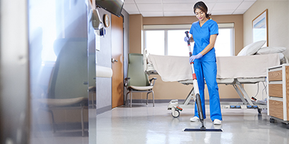 worker cleaning patient room floors
