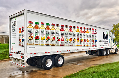 Semi-truck with fleet vehicle wrap with images of bottles of juice.