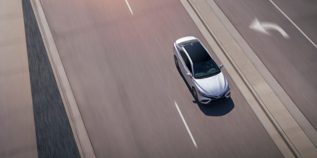Silver sedan driving on a highway.