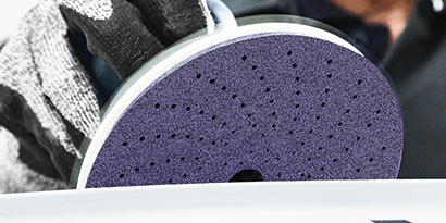 technician holding a cubitron II sanding disc on a festool
