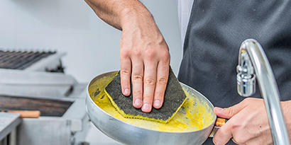 A kitchen worker cleans a pan with Scotch-Brite™ Dual Purpose Scour Pad 96HEX.
