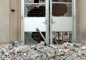 Despite piles of debris outside a building, the glass doors remain intact.