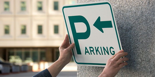 Person mounting parking sign to concrete wall
