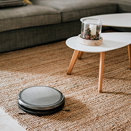 a wireless, robotic vacuum cleaning a living room carpet.