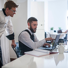 A chef and an administrator look at a laptop computer in an upscale restaurant.