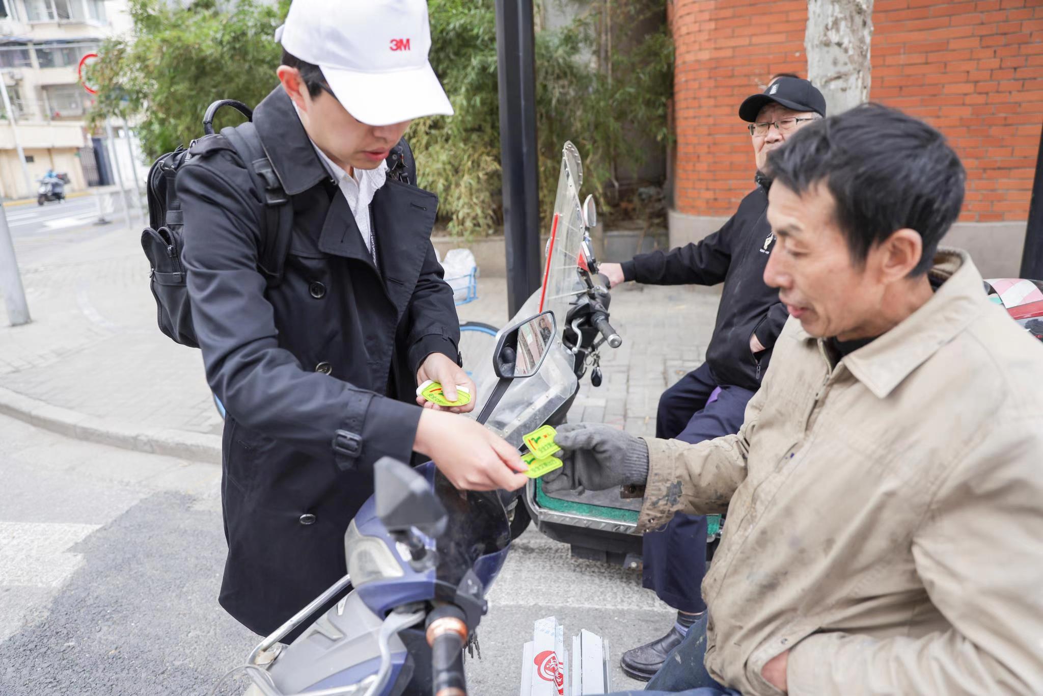 3M志愿者向过路的非机动车驾驶员赠送反光贴