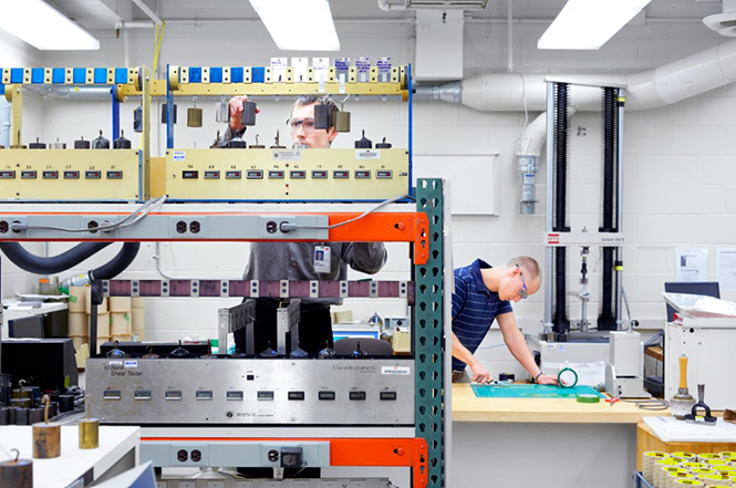 Two men in a 3M lab testing numerous electronics bonding capabilities.
