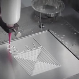 Video still of a robot arm applying a thin bead of adhesive to a part
