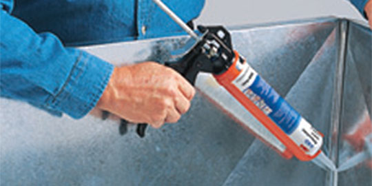 Adhesive or sealant being applied over seam in metal sheet
