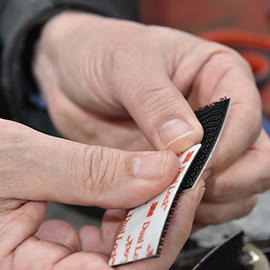 Image of hands pressing together a strip of 3M™ Dual Lock™ in a work setting