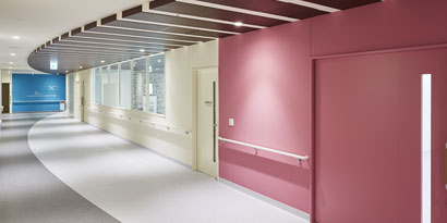 A hallway in a commercial building displays red, yellow and wood-grain finishes, including 3M™ DI-NOC™.
