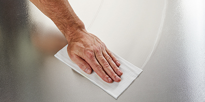 A worker cleans stainless steel surface with a Scotch-Brite™ Kitchen Cleaner & Degreaser Wipe.

