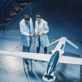 在实验室里，两名穿着白大褂的人员在飞机模型旁进行讨论。